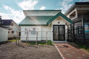 une petite maison blanche avec une porte noire dans l'établissement 南町ハウス, à Biei