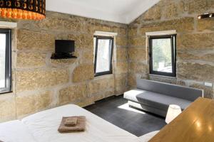 a bedroom with a couch and a tv in a stone wall at Villa Lugar do Pego in Tondela