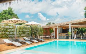 a pool with chairs and umbrellas next to a house at The Wander Nest Villas in Panglao Island