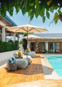 a pool with four umbrellas and lounge chairs and a pool at The Wander Nest Villas in Panglao Island