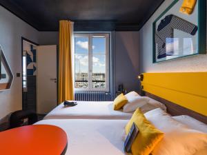 een hotelkamer met twee bedden en een raam bij ibis Styles Saint Malo Centre Historique in Saint-Malo +131 foto's