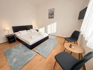 a bedroom with a bed and two chairs and a table at Zama Apartman in Hajdúszoboszló +23 photos