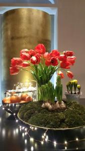 eine Vase mit roten Blumen auf einem Tisch mit Lichtern in der Unterkunft La Cupola del Vaticano in Rom