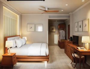 a bedroom with a bed and a desk and a television at Hotel Kiridara Luang Prabang in Luang Prabang