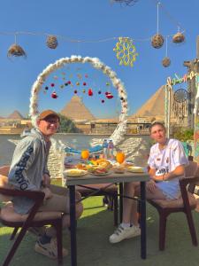 Due persone sedute a un tavolo di fronte alle piramidi di Leeda Pyramids View a Il Cairo