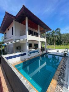 a villa with a swimming pool in front of a house at phu petra villa in Ao Nang 
