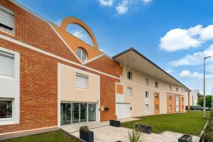 een bakstenen gebouw met een grote cirkel aan de zijkant bij Sweetly Isatis Mérignac Hôtel de ville in Mérignac