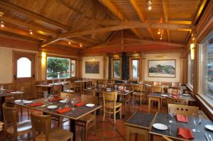 um restaurante com mesas e cadeiras de madeira e janelas em Del Bosque Apart Hotel em Ushuaia