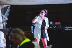 Eine Frau, die mit einem Mikrofon auf einer Bühne steht. in der Unterkunft Camping 3 étoiles - Piscine - eeicbi in Le Change + 148 Fotos