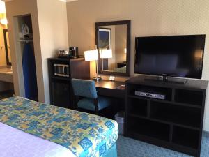 a hotel room with a bed and a flat screen tv at Regency Inn at San Francisco Airport in San Bruno