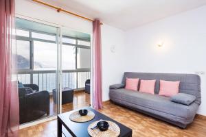 ein Wohnzimmer mit Couch und großem Fenster in der Unterkunft Apartamento Vistas Al Mar y al Teide in Puerto de la Madera