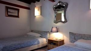 een slaapkamer met 2 bedden en een spiegel aan de muur bij DoMarie in Venetië