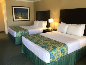a hotel room with two beds and a lamp at Regency Inn at San Francisco Airport in San Bruno