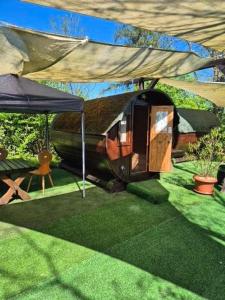 a small house with a tent in the grass at Mini Hotel Übernachten Im Gurkenfass in Lübbenau