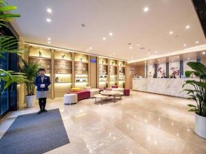 uma mulher em pé numa sala grande com um lobby em Lavande Hotels·Yichang Wanda Plaza em Yichang