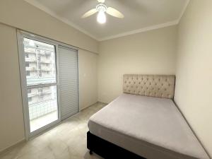 une chambre avec un lit et un ventilateur de plafond dans l'établissement Apartmento com 3 dorm no Canto do Forte, à Praia Grande