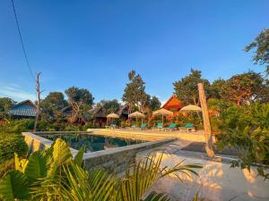 a resort with a swimming pool and tables and umbrellas at Hideout Sunset in Nusa Penida