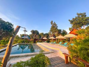 a pool at a resort with chairs and umbrellas at Hideout Sunset in Nusa Penida