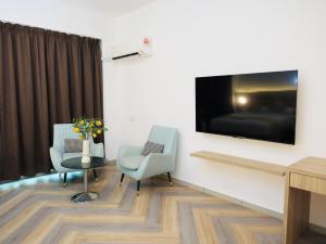 a room with two chairs and a tv on a wall at BIG TREE HOTEL in Temerloh