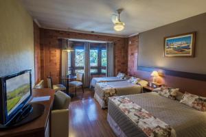 a hotel room with two beds and a flat screen tv at Hotel Serra Nevada in Canela