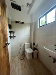 a bathroom with a toilet and a sink at The Hat Trick Hostel in Basdiot