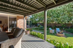 een patio met een houten terras met stoelen en een tafel bij Bliss at Jervis Bay - pet-friendly Vincentia home in Vincentia