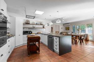 een keuken met witte kasten en een tafel. bij Bliss at Jervis Bay - pet-friendly Vincentia home in Vincentia +43 foto's