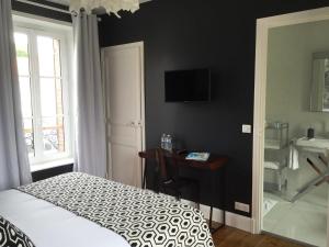 Un dormitorio con una cama, un escritorio y un televisor. en Villa la Ruche, en La Baule