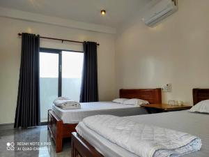 a bedroom with two beds and a window with a view at Nest Homestay in Cat Tien