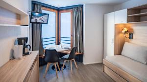een kamer met een bureau, een bed en een raam bij Résidence Odalys Tourotel in Val Thorens