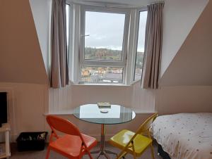 een kamer met een tafel, stoelen en een raam bij Hill View Studio in Hawick