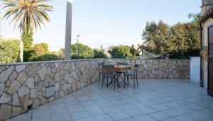 a patio with a table and chairs on a stone wall at La Casetta di Josh in Marsala
