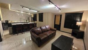 a living room with a leather couch and a kitchen at Luxury Suites Seoul Consulado in Zaragoza