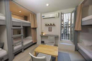 a dorm room with bunk beds and a table and a desk at Bud Brew Beyond Dispensary and Hotel in Bangkok