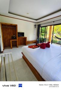 ein Schlafzimmer mit einem großen weißen Bett mit roten Kissen in der Unterkunft Lanta Buddy Resort in Ko Lanta