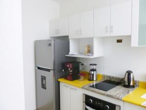 Una cocina con gabinetes blancos y un refrigerador de acero inoxidable. en Edificio California en Centro Historico, en Lima