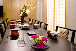 een lange tafel met bloemen erop bij onna resort nakadomari ビーチまで車で4分 最大12名OK 中庭付き貸切ヴィラでくつろぐ恩納村ステイ in Onna