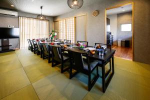 een lange eetkamer met een lange tafel en stoelen bij onna resort nakadomari ビーチまで車で4分 最大12名OK 中庭付き貸切ヴィラでくつろぐ恩納村ステイ in Onna