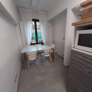 een eetkamer met een tafel, stoelen en een televisie bij Grattacielo Rooms in Turijn
