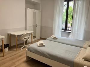 een slaapkamer met twee bedden, een bureau en een raam bij Grattacielo Rooms in Turijn