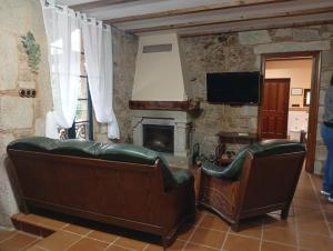 a living room with two leather chairs and a fireplace at A Casa da Rianxeira in A Pobra do Caramiñal