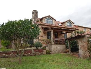 a large brick house with a tree in the yard at A Casa da Rianxeira in A Pobra do Caramiñal