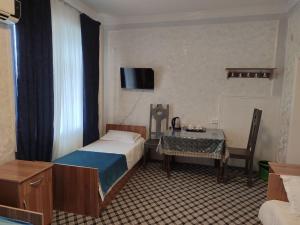 a bedroom with a bed and a table and a television at ASR HOSTEl in Andizhan
