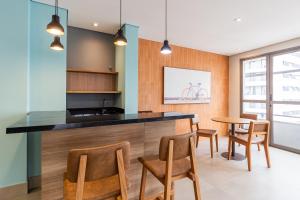 a kitchen with a counter and chairs and a table at Apê novo, moderno, a 50 metros metrô República in São Paulo