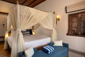 a bedroom with a canopy bed and a blue couch at Oruva Beachside Villa in Galle