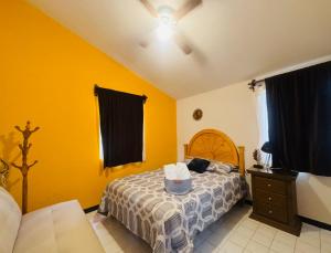 a bedroom with a bed and yellow walls at Casa Orquídeas Oaxaca in Oaxaca City