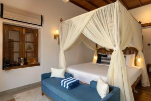 a bedroom with a canopy bed and a blue couch at Oruva Beachside Villa in Galle