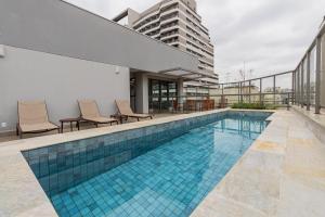 a swimming pool with chairs and a building at Apê novo, moderno, a 50 metros metrô República in São Paulo