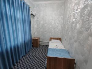 a small room with a bed and a blue curtain at ASR HOSTEl in Andizhan