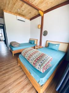 two beds in a room with wooden floors at Nhà Dâu Homestay in Muong Cha